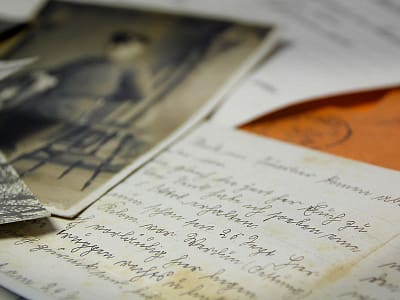 Een close-up van oude handgeschreven brieven en nostalgische zwart-witfoto's, die mij eraan herinneren om het leven in flow te leven.