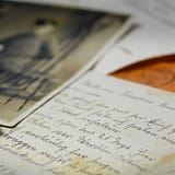 Een close-up van oude handgeschreven brieven en nostalgische zwart-witfoto's, die mij eraan herinneren om het leven in flow te leven.