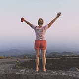 Middelbare vrouw met armen gespreid op muurtje voor uitzicht